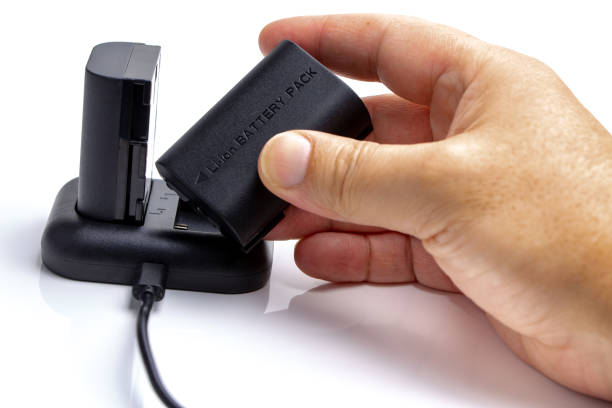 istock Man manipulating Camera battery and charger 1128336958