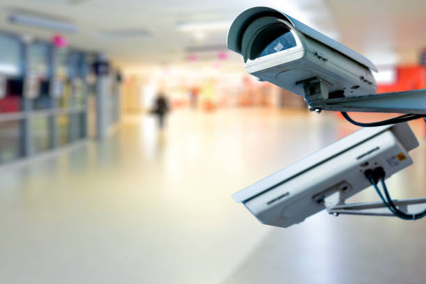 Modern CCTV camera on a wall. with blurred coloreful background. Modern CCTV camera on a wall. Concept of surveillance and monitoring. cctv camera overlay stock pictures, royalty-free photos & images