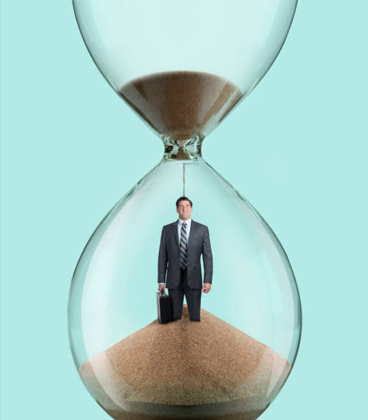 istock Businessman Standing Inside Hourglass As Sand Pours On His Head 1128338895