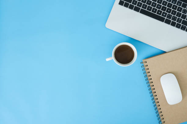 istock Minimal work space - Creative flat lay photo of workspace desk. Top view office desk with laptop, notebooks and coffee cup on blue color background. Top view with copy space, flat lay photography. 1128343715