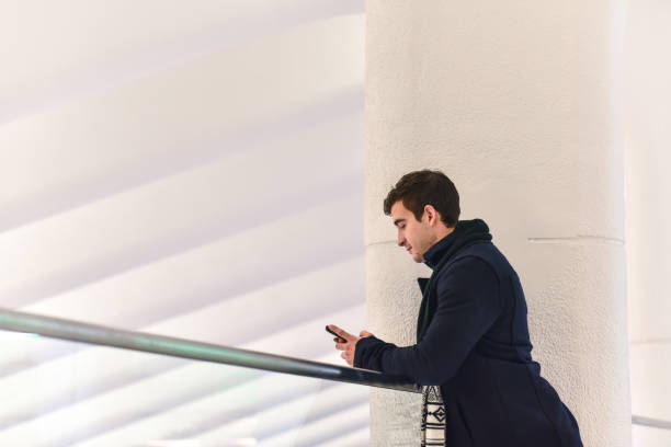 istock Young Man Leaning on Banister on Mobile Phone 1128370644
