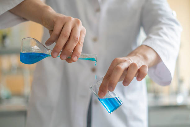 istock chemical researcher work with two beakers with blue liquid b 1128387158
