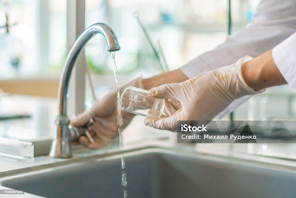 scientist wash beaker from poisonous acid after experiments b Water Stock Photo