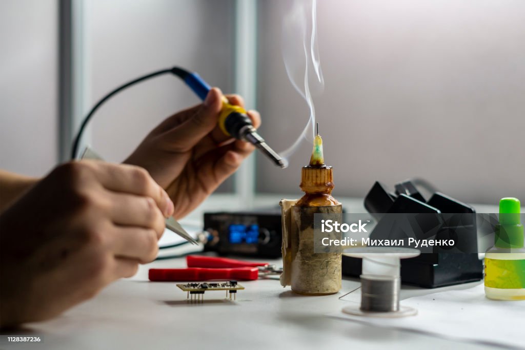 soldering iron with smoke from boiling rosin or colophony b soldering iron with smoke from boiling rosin or colophony Backgrounds Stock Photo