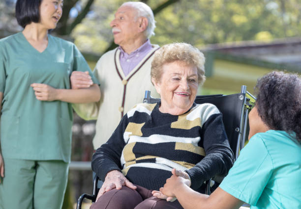 istock Seniors relaxing in nursing home park joking with nurses 1128390600
