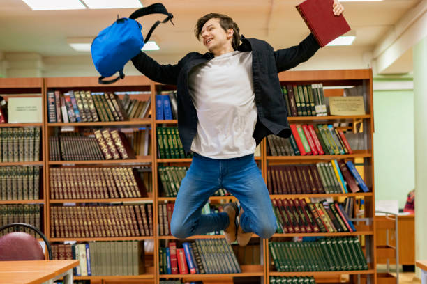 istock happy student jumping with books and backpack b 1128391474