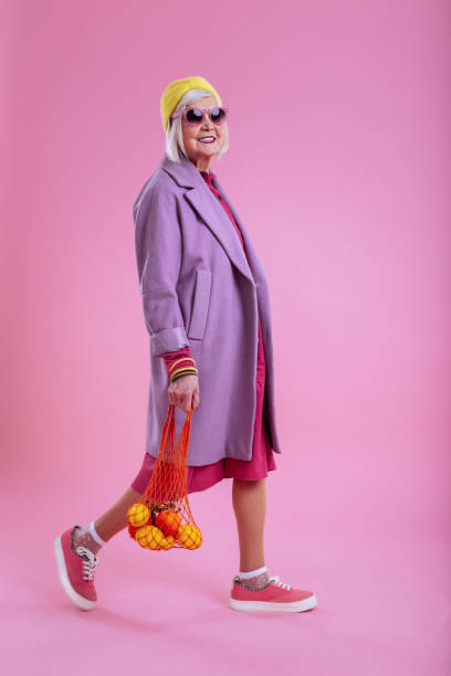 istock Cute elderly lady wearing pink sneakers walking with bag 1128391639