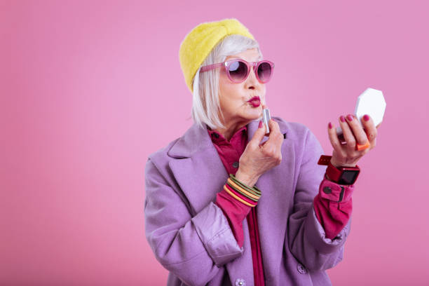 Cute lovely retired woman making funny face coloring lips