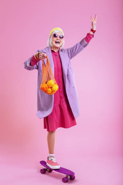 istock Modern elderly lady riding skate with string bag of fruits 1128391685