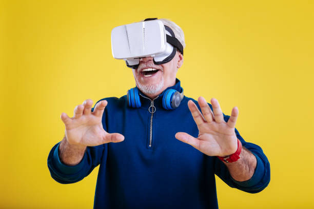 istock Grey-haired retired man feeling entertained wearing VR glasses 1128393202