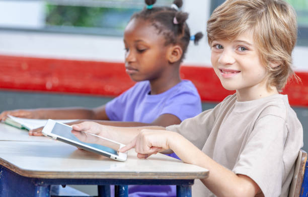 istock Schoolchildren sitting at the desk studying with the tablet 1128393237