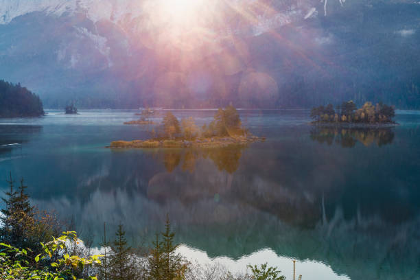 istock First sun rays on the mountain lake Eibsee in Bavarian Alps. sunrise over mountains and small island with reflection 1128394449