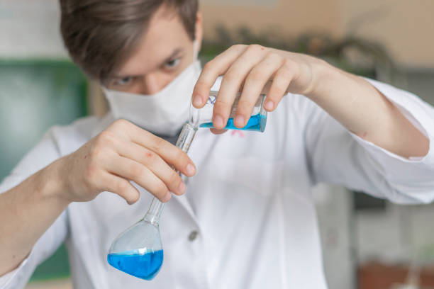 chemical researcher work with two beakers with blue liquid
