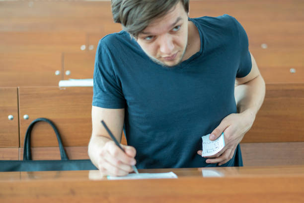 young student cheat at the exams in school. write off cheat sheet