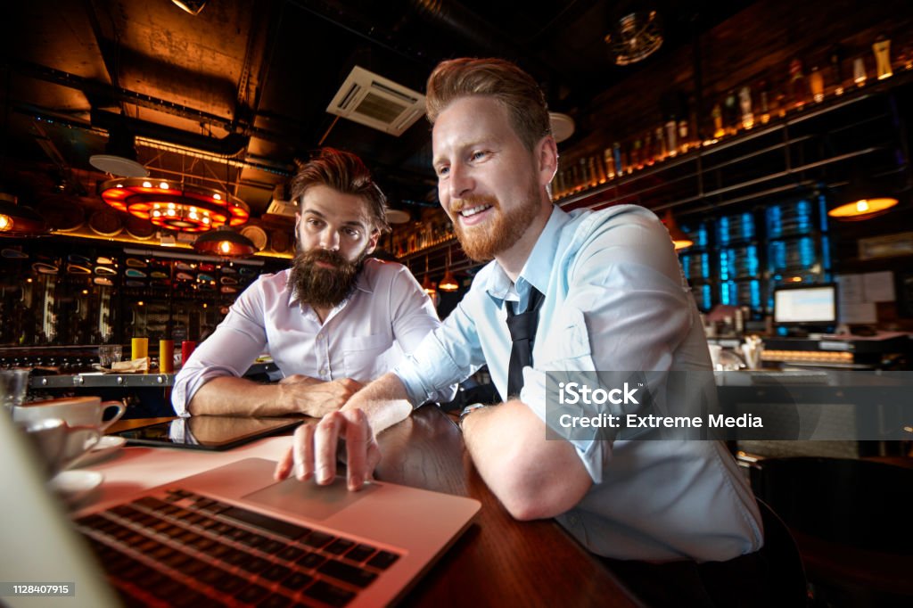 Zwei Geschäftsleute Arbeiten unterwegs auf einem Laptop in einem Café zusammen - Lizenzfrei Lokal Stock-Foto