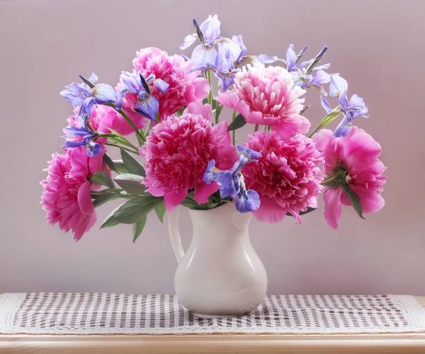 istock peonies and irises in a jug on the table. 1128412064