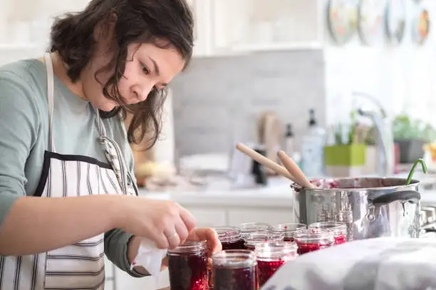 Eurasian teen making homemade raspberry and blackberry jam in Vancouver, British Columbia, Canada