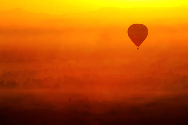 Hot air balloon flying in Luxor, Egypt. In a beautiful sunrise with foggy orange background.