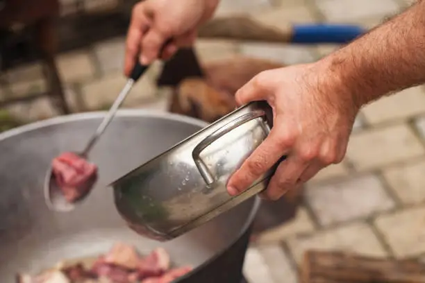 Photo of Cook adds pieces of lamb in a cauldron