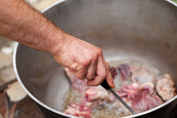 istock Cook mixes lamb pieces in cauldron 1128419144