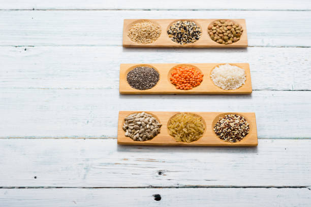 зерна, семена, белый деревянный стол - processed grains rice variation in a row стоковые фото и изображения