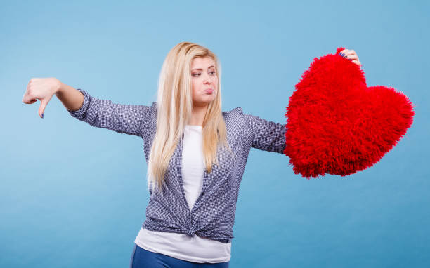 istock Woman holding red heart showing thumb down 1128429232