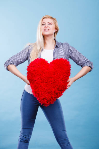 istock Happy woman holding red pillow in heart shape 1128429258