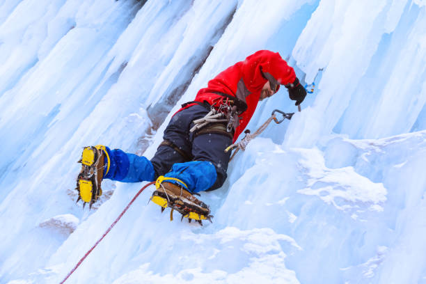 istock rock climber screwing ice screw into glacier surface 1128430676