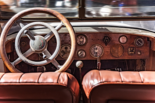 Cabin from inside a retro car. Wooden dashboard and steering wheel.