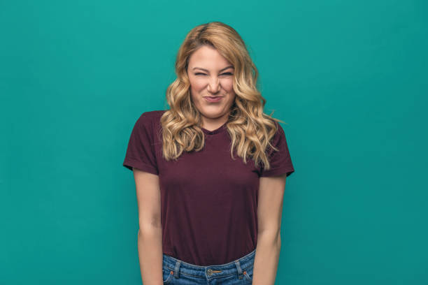 istock A young woman is squinting a sour grimace while standing against blue background. 1128435029
