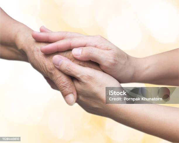 Caregiver Carer Hand Holding Elder Hand For Hospice Care Philanthropy Kindness To Disabled Old People Concept With Gold Bokeh Backgroundhappy Mothers Day Stock Photo - Download Image Now