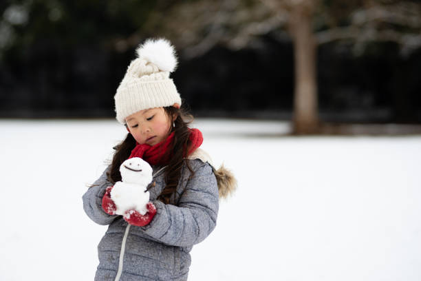 fille jouant dans le parc enneigé - child winter snow asian ethnicity photos et images de collection