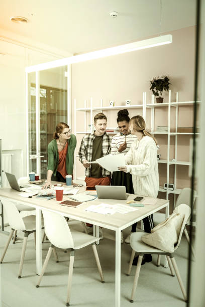 istock Students and teacher studying in light spacious room together 1128444358