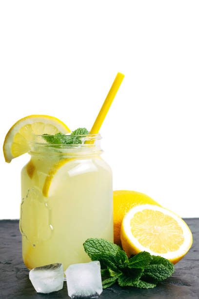 istock Refreshing lemonade drink with lemon slice and mint in the jar on dark table and white background 1128444585