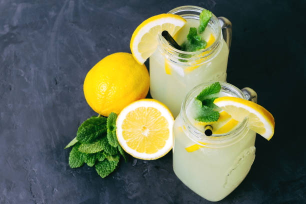 Refreshing lemonade drink with lemon slice and mint in the jar on dark background Refreshing lemonade drink with lemon slice and mint in the jar on dark background. mason jar lemonade stock pictures, royalty-free photos & images