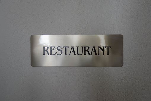 Sign with restaurant written on it on a white wall