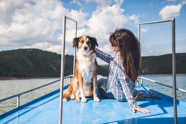istock Young woman enjoys a boat ride on river with her dog. 1128445801
