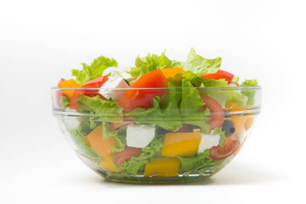 istock Greek salad in a glass bowl Isolated on white background 1128445832