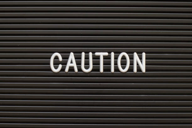 istock Black color felt letter board with white alphabet in word caution background 1128446719