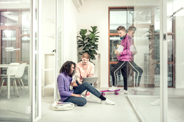 istock Two students sitting on the floor revising material together 1128448673
