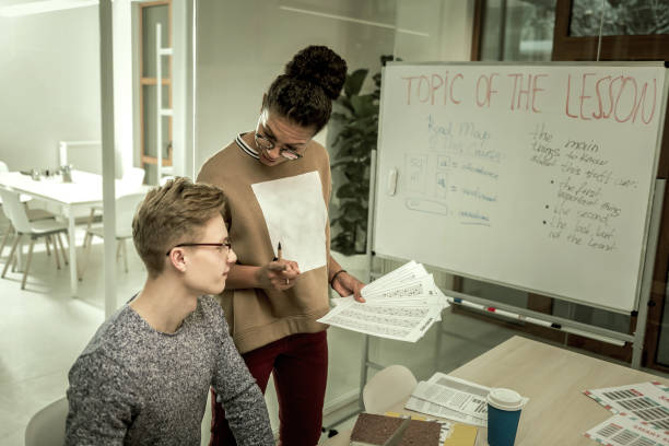 istock Young teacher wearing glasses explaining student his mistakes 1128448724