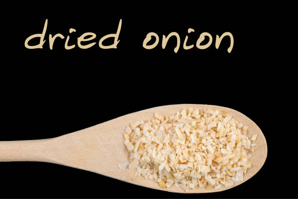 dried onion on wooden spoon isolated on black background