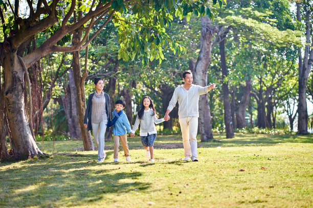 istock happy asian family walking in park 1128452685