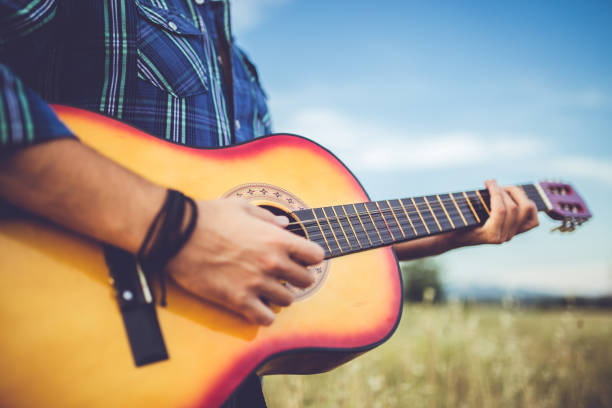 istock Man standing in wheat field and playing guitar. 1128455177
