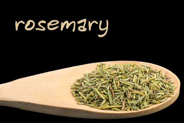 rosemary on wooden spoon isolated on black background