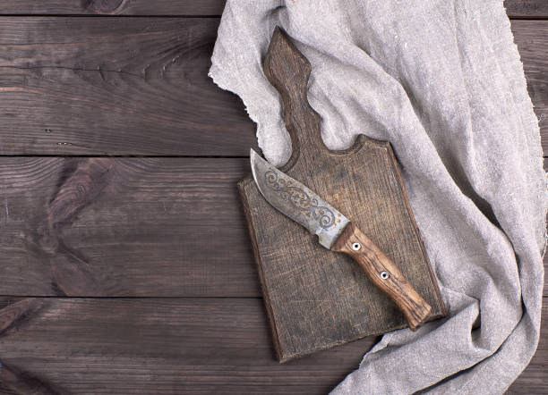 old wooden kitchen board and vintage knife on a brown wooden background, top view