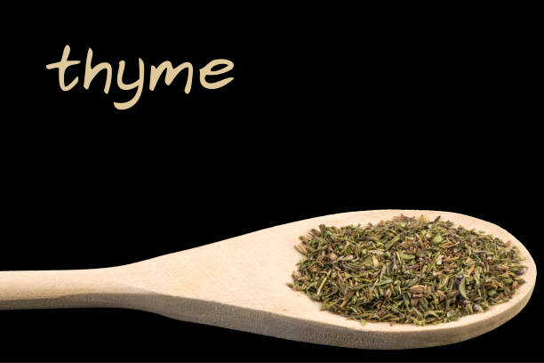 istock thyme on wooden spoon isolated on black background 1128459505