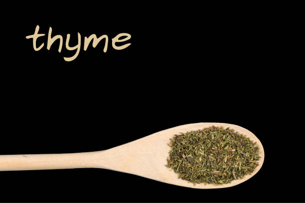 istock thyme on wooden spoon isolated on black background 1128459522