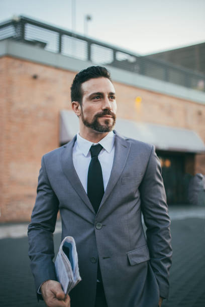 istock Modern man in suit holding newspaper 1128459537
