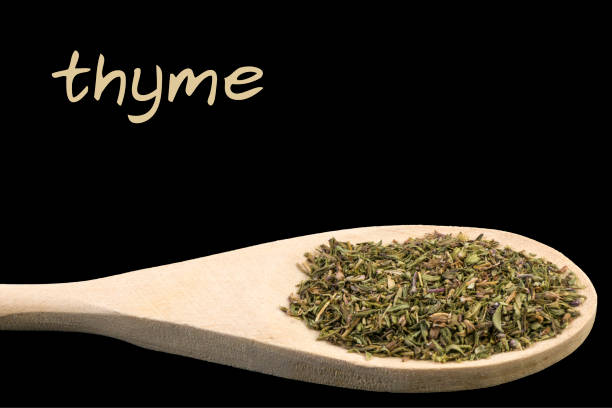 istock thyme on wooden spoon isolated on black background 1128459743